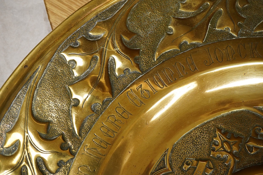An embossed brass arts and crafts alms charger with inscriptions, 51cm in diameter